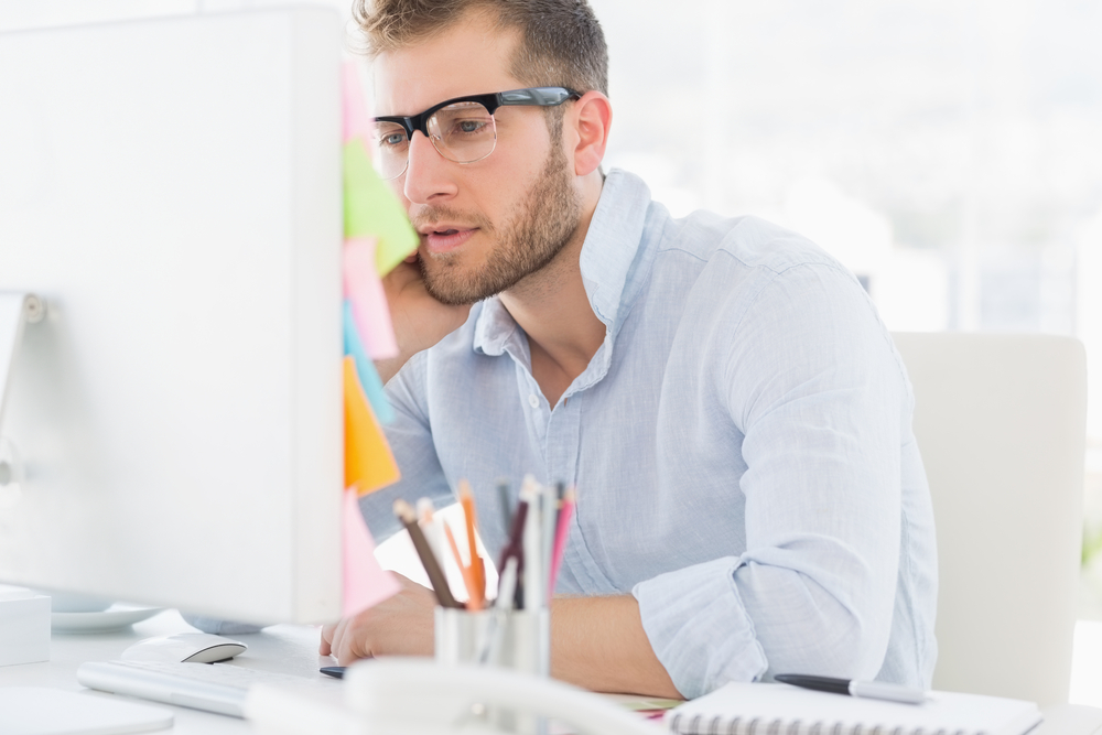 Concentrated young man using computer in a bright office